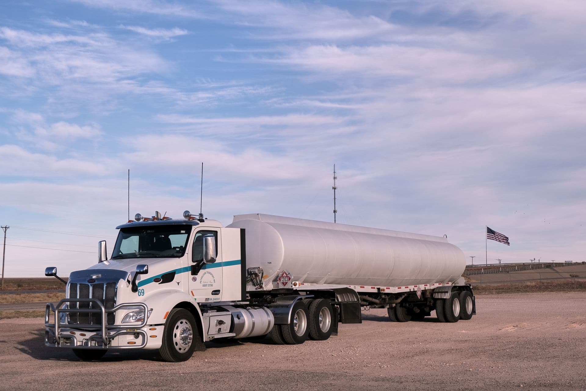 White fuel tanker truck parked with an American flag in the background
